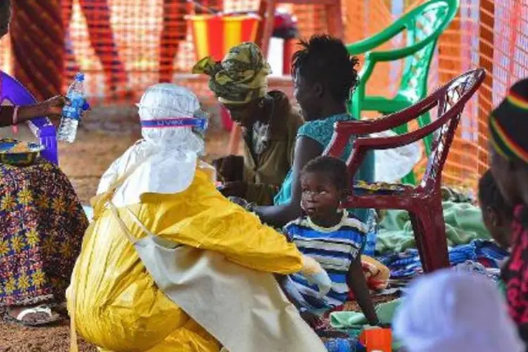 
	Membro da M&eacute;dicos sem Fronteiras alimenta crian&ccedil;a com ebola, em Serra Leoa
 (Carl de Souza/AFP)