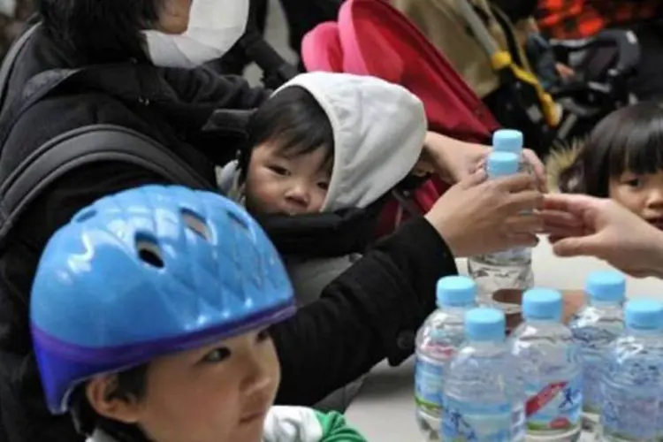 Mãe compra garrafas de água para crianças em Tóquio: na quarta, radiação chegou a 210 becquerels (Yoshikazu Tsuno/AFP)