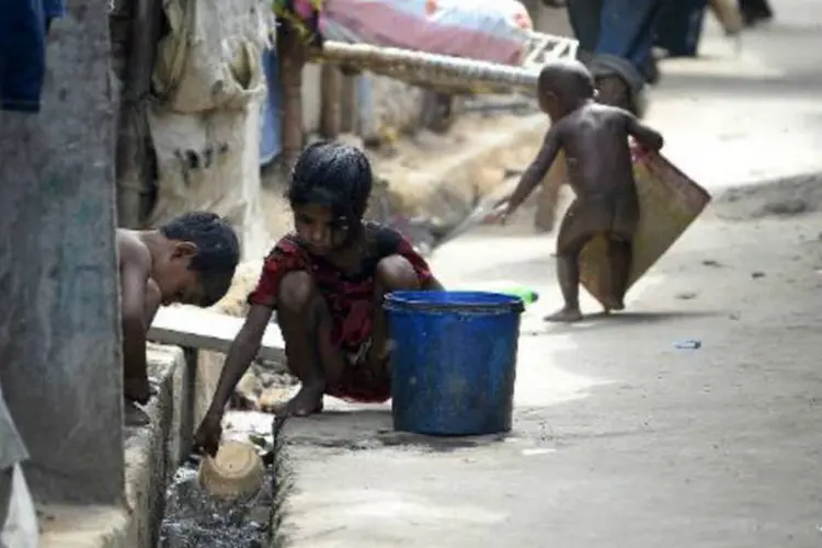 
	Crian&ccedil;as indianas coletam &aacute;gua suja em Ghazipur, no leste de Nova Deli
 (Chandan Khanna/AFP)