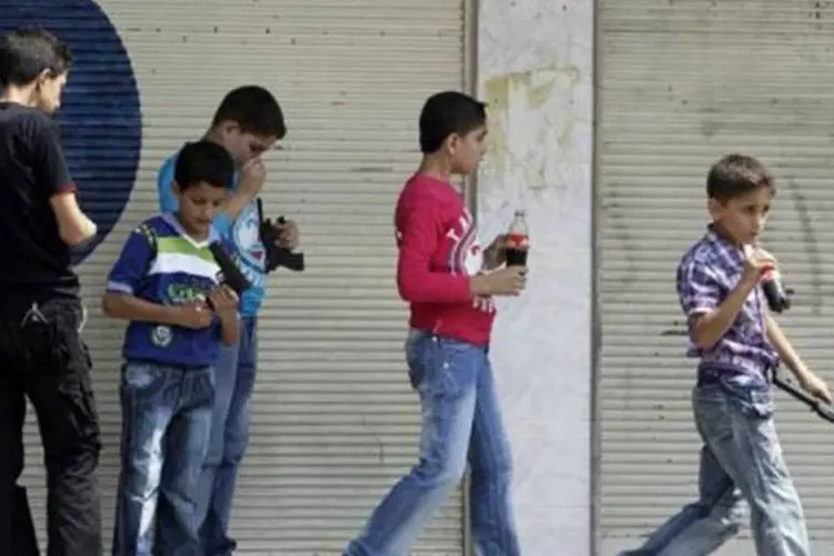 Crianças brincam com armas de brinquedo em Homs, na Síria: cidade é uma das mais reprimidas pelo governo (Joseph Eid/AFP)