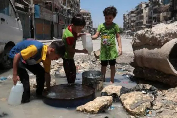 Crianças sírias pegam água em área controlada pelos rebeldes em Alepo (Zein Al-Rifai/AFP)