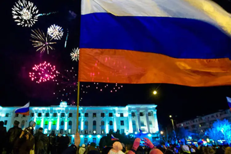 Pessoas observam fogos de artifício e sacodem bandeiras russas durante comemoração do referendo que define a independência da Crimeia (REUTERS/Thomas Peter)