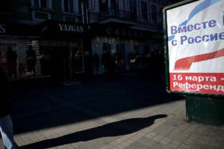 
	Homem passa ao lado de cartaz que informa sobre referendo na Crimeia em Simferopol: a Ucr&acirc;nia &quot;se reserva o direito de recorrer a todos os meios necess&aacute;rios para deter a invas&atilde;o militar russa&quot; (Filippo Monteforte/AFP)