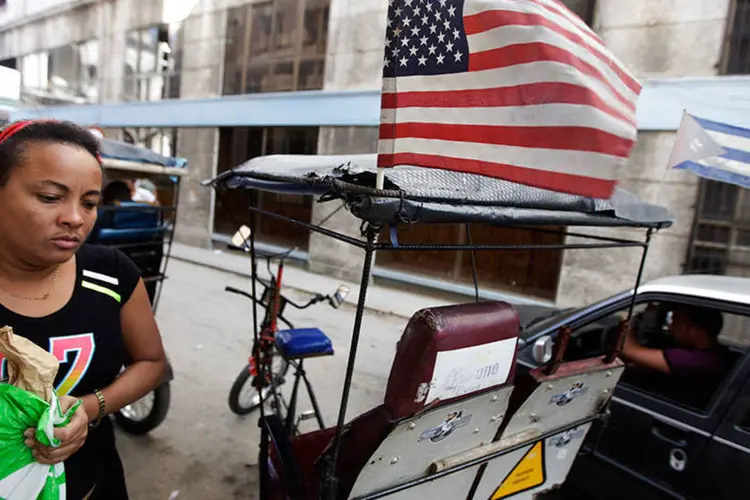 
	Mulher passa por bici-t&aacute;xi com as bandeiras dos Estados Unidos e de Cuba em Havana
 (REUTERS/Enrique De La Osa)