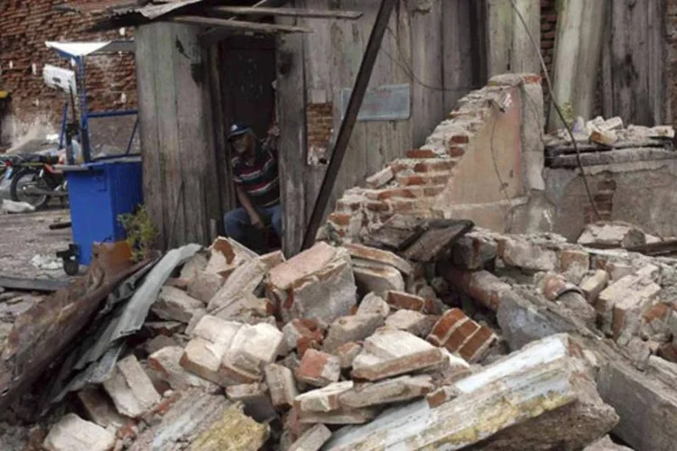 Um homem é visto sentado dentro de sua casa, danificada pelo furacão Sandy, em Santiago de Cuba (REUTERS/Miguel Rubiera)