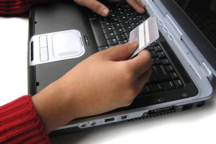 Mãos usando cartão de crédito no computador (Stock.xchng)