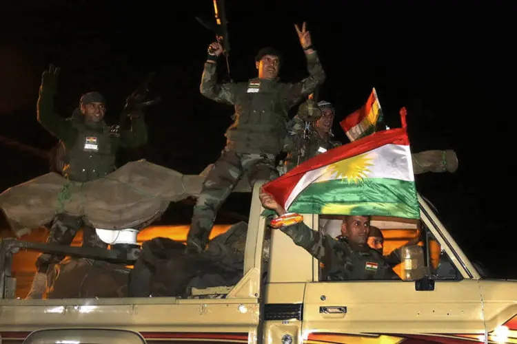 
	Combatentes curdos peshmerga agitam uma bandeira enquanto se movem para a cidade s&iacute;ria de Kobani, na fronteira com a Turquia
 (Yannis Behrakis/Reuters)