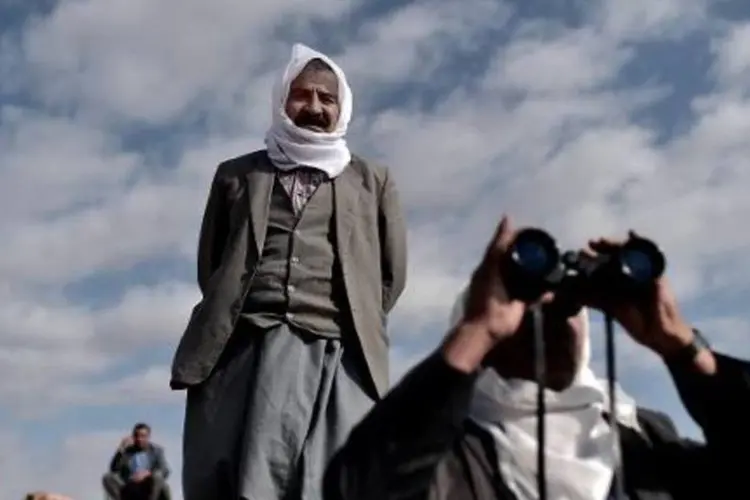 
	Curdos observam do lado turco da fronteira batalha de Kobane: as for&ccedil;as curdas da S&iacute;ria anunciaram nesta quinta-feira que respeitar&atilde;o o acordo de tr&eacute;gua
 (Aris Messinis/AFP)