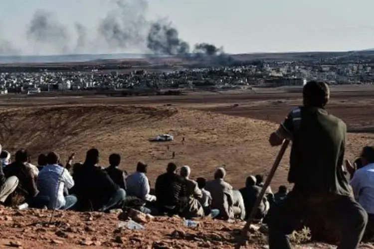 
	Curdos observam em colina da Turquia a fuma&ccedil;a provocada pelos combates na cidade s&iacute;ria de Kobane: os curdos acusam o poder central turco de n&atilde;o proteger a popula&ccedil;&atilde;o local
 (Aris Messinis/AFP)