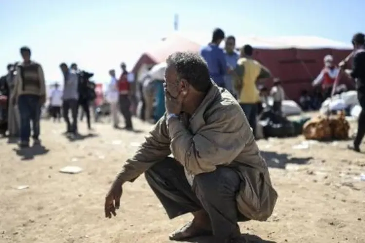 Curdos sírios, que fugiram da violência, aguardam na fronteira com a Turquia (Bulent Kilic/AFP)
