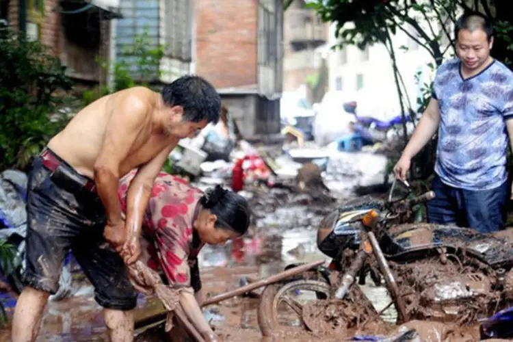 
	Moradores tentam limpar ruas ap&oacute;s fortes chuvas em Yiliang: equipes de emerg&ecirc;ncia resgataram dois moradores ap&oacute;s o deslizamento, que encobriu 16 casas
 (AFP)