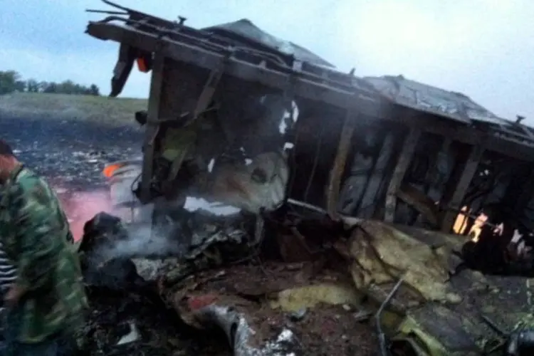 
	Homem caminha em meio aos destro&ccedil;os do Boeing 777: insurgentes ucranianos encontraram caixa-preta do avi&atilde;o
 (AFP/Getty Images)