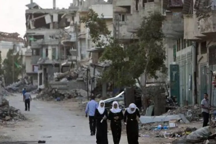 Pessoas caminham diante de destruição na Faixa de Gaza (Mahmud Hams/AFP)