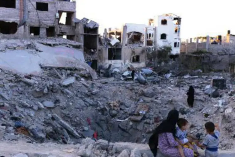 Mulher e crianças observam destruição no local onde ficava a casa da família em Gaza (Roberto Schmidt/AFP)