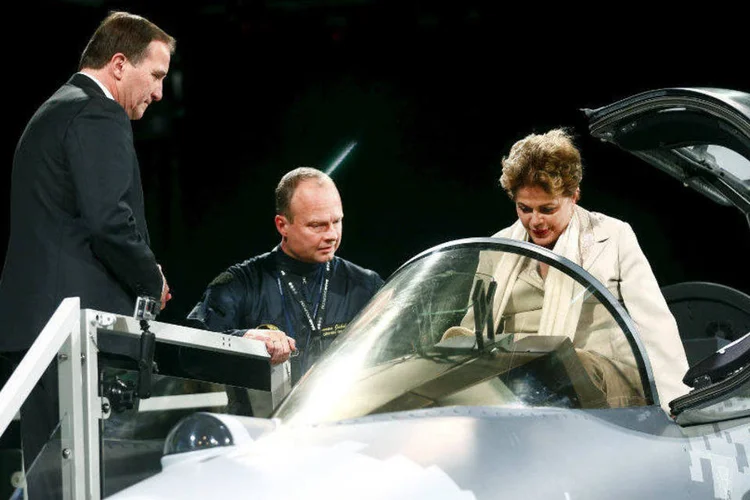 
	Piloto de testes e o premi&ecirc; da Su&eacute;cia, Stefan Lofven (e), mostram para a presidente Dilma Rousseff um ca&ccedil;a Gripen
 (Stefan Jerrevang/TT News Agency/Reuters)