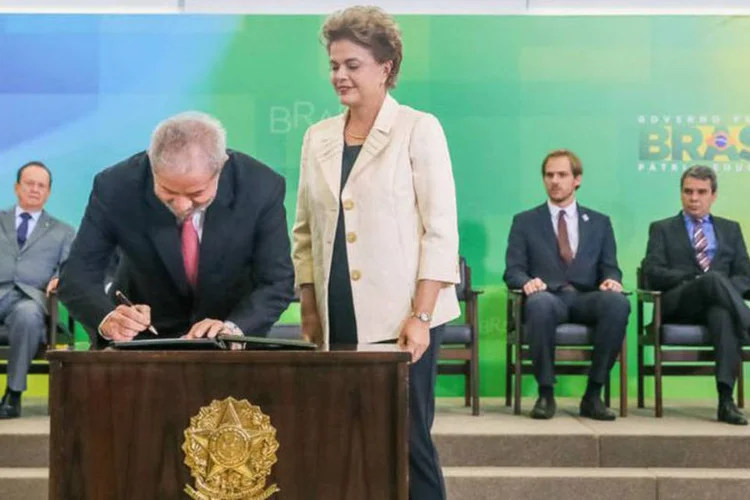 
	Presidente Dilma Rousseff observa ex-presidente Lula assinando seu termo de posse como ministro
 (Roberto Stuckert Filho / PR / Agência Brasil)