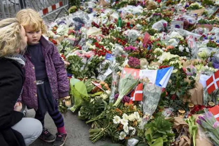 
	O mundo encolhe: mulher e filha prestam homenagem &agrave;s v&iacute;timas de Paris, em frente &agrave; embaixada francesa em Copenhague, na Dinamarca.
 (Reuters)