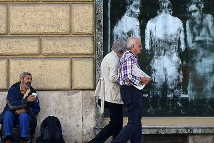 Homem pede dinheiro em frente a um banco do centro da capital italiana, Roma (Filippo Monteforte/AFP)