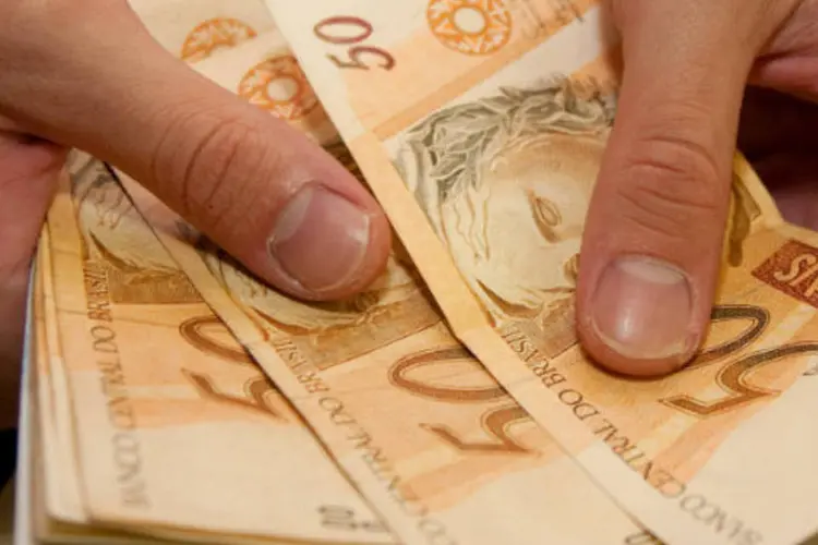 Pessoa conta notas de cinquenta reais - dinheiro (Marcos Santos/USP Imagens)