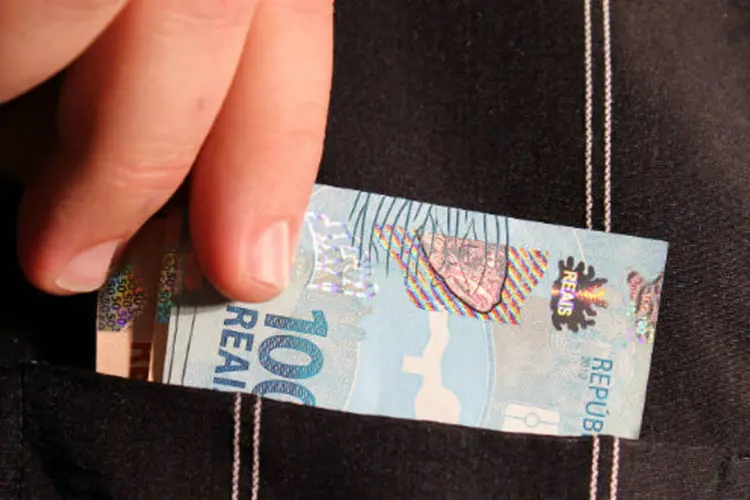 Pessoa retira dinheiro do bolso - notas de real (Marcos Santos/USP Imagens/Site Exame)