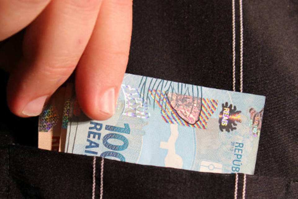 Pessoa retira dinheiro do bolso - notas de real (Marcos Santos/USP Imagens)