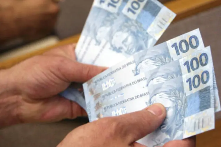 Dinheiro: homem segura notas de real (Adriano Machado/Bloomberg)