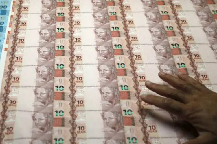 
	Dinheiro: m&atilde;o em cima de notas de real
 (REUTERS/Sergio Moraes)