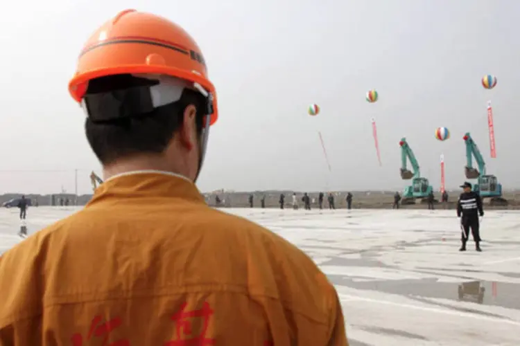 Trabalhador da construção caminha pelo local onde será construído o parque da Disney em Xangai, na China (Qilai Shen/Bloomberg)