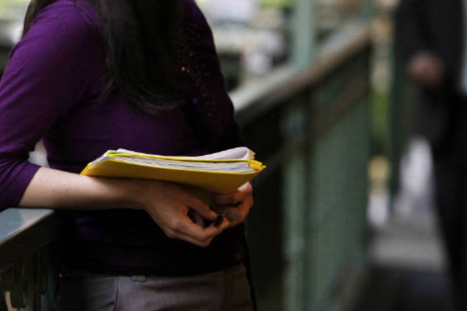 Mulher segura pasta com currículo e documentos em feira de empregos (Patrick T. Fallon/Bloomberg)