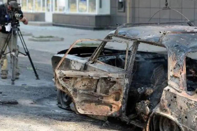 Cinegrafista filma automóvel incendiado no centro de Donetsk, no leste da Ucrânia (Francisco Leong/AFP)