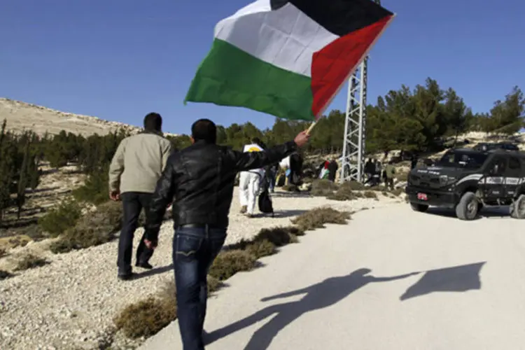 Manifestante palestino segura bandeira enquanto chega a área conhecida como E1, que conecta as duas partes ocupadas por Israel na Cisjordânia (Ammar Awad/Reuters)