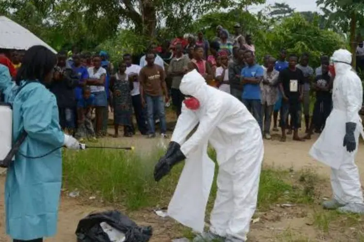 Habitantes de Bajol observam membros da Cruz Vermelha desinfectando suas roupas (Dominique Faget/AFP)