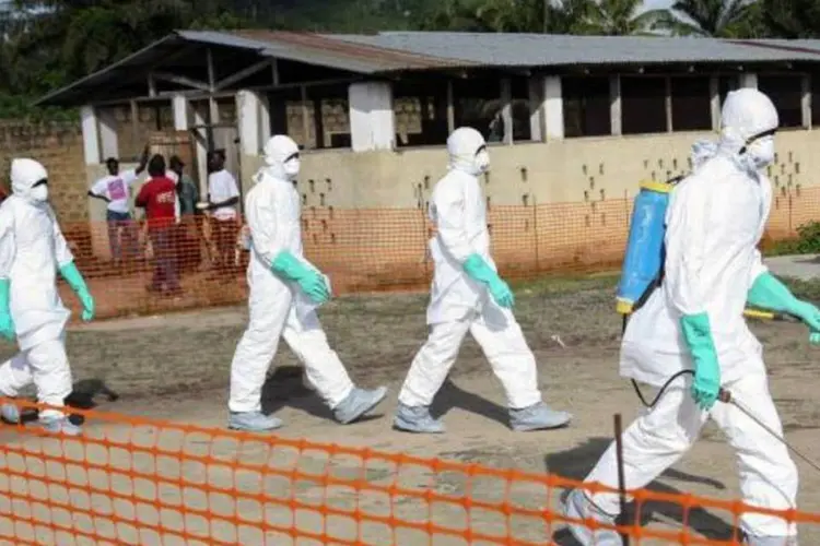 
	Trabalhadores da &aacute;rea de sa&uacute;de isolam &aacute;rea onde uma mulher morreu v&iacute;tima de ebola
 (Ahmed Jallanzo/Agência Lusa/Agência Brasil)