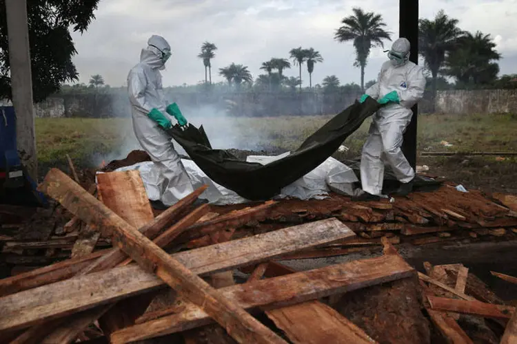 
	Membros da equipe funer&aacute;ria do Minist&eacute;rio da Sa&uacute;de da Lib&eacute;ria incineram os corpos de v&iacute;timas do ebola, em Marshall
 (John Moore/Getty Images)