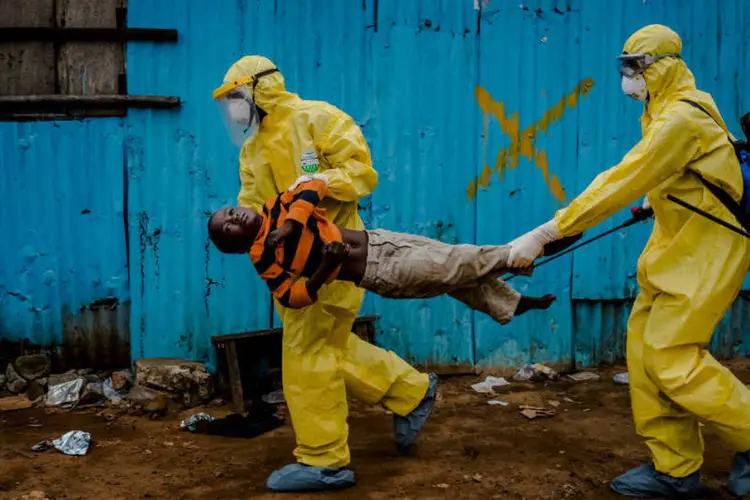 
	Profissionais da sa&uacute;de carregam paciente suspeito de ebola
 (Daniel Berehulak/Reuters)