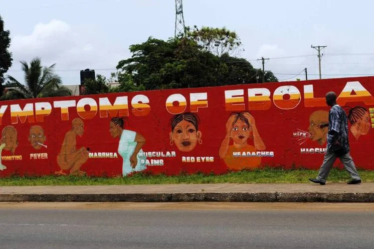 Homem caminha próximo a mural que mostra os sintomas do Ebola em Monrovia, na Libéria (Reuters/James Giahyue)