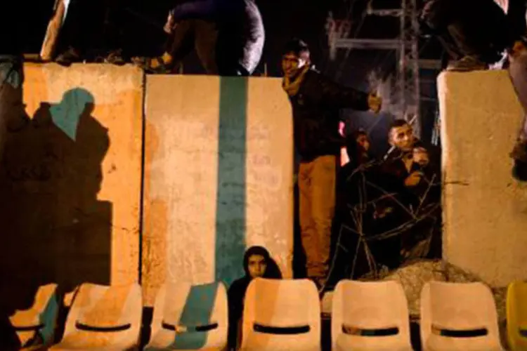
	Parentes dos presos palestinos aguardam sua sa&iacute;da em Erez: gritos de alegria e fogos de artif&iacute;cio se misturaram no bairro palestino de Bet&acirc;nia (MAHMUD HAMS/AFP)