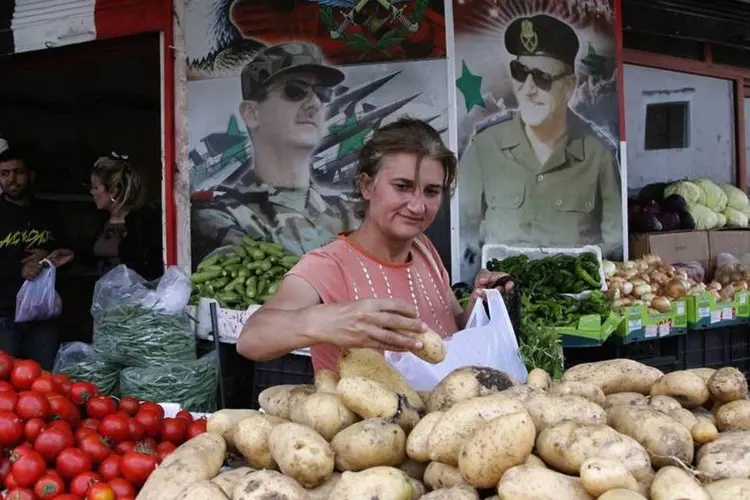 Mulher compra batatas de uma barraca na cidade de al-Qardaha, próxima de Lataquia, na Síria (Khaled al-Hariri/Reuters)