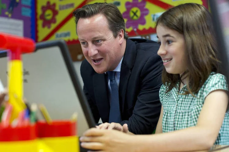 David Cameron com uma aluna na aula de computação de uma escola de Londres, na Inglaterra (David Bebber/WPA Pool/Getty Images)