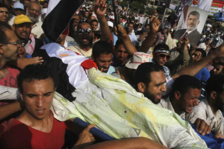 
	Apoiadores do presidente deposto do Egito Mohamed Mursi carregam o corpo de um manifestante morto em atos de viol&ecirc;ncia em frente ao quartel da Guarda Republicana, no Cairo
 (Khaled Abdullah/Reuters)