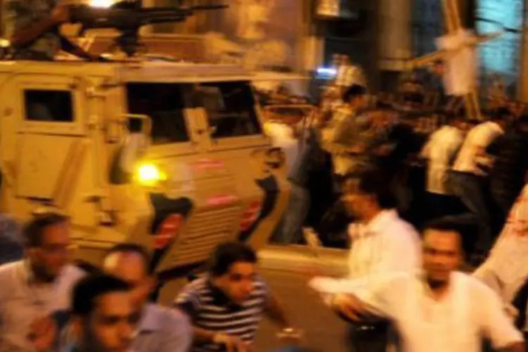 Cristãos fogem das forças de segurança, que atiraram para o alto: após o incidente, as autoridades egípcias decretaram um toque de recolher no centro do Cairo
 (Mohammed Hossam/AFP)