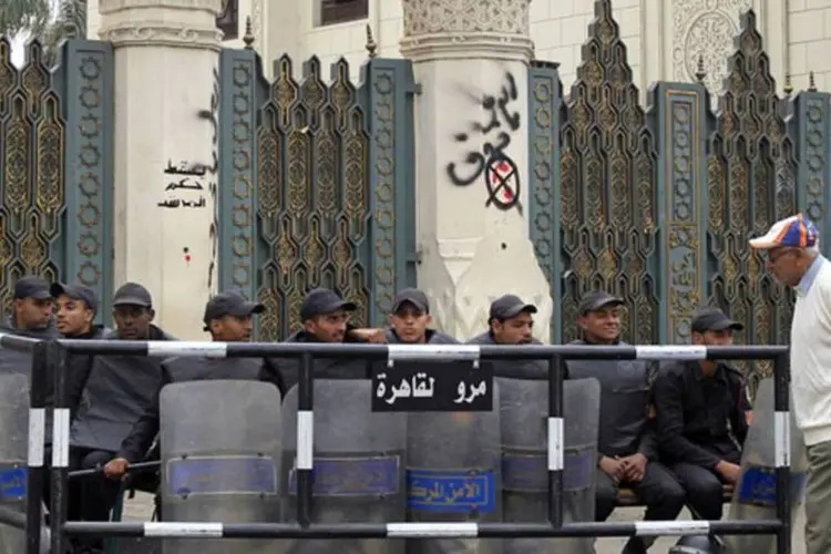 
	Um homem caminha em frente &agrave; tropa de choque no port&atilde;o do pal&aacute;cio presidencial em Cairo: Os confrontos foram retomados com viol&ecirc;ncia
 (REUTERS)