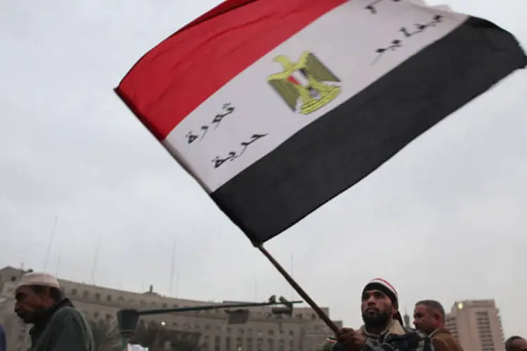 
	Homem carrega a bandeira do Egito:&nbsp;dos 43 acusados, 27 - em sua maioria estrangeiros, incluindo 20 americanos - foram julgados &agrave; revelia e condenados a cinco anos pris&atilde;o.
 (Jeff J Mitchell/Getty Images)