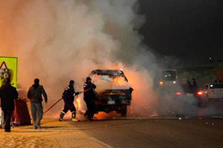 Bombeiros egípcios extinguem fogo do lado de fora do estádio do Cairo, durante confrontos entre torcedores do Zamalek e as forças de segurança  (AFP)