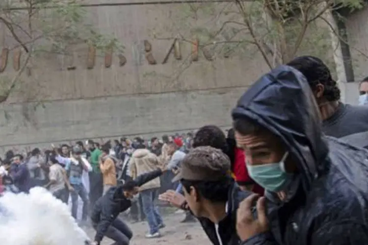 Manifestantes tentam se proteger das bombas de gás lacrimogêneo no Egito
 (Michele Sibiloni/AFP)