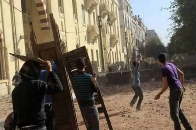 Manifestante egípcio joga pedras contra forças policiais no Cairo (AFP/Mohammed Abed)