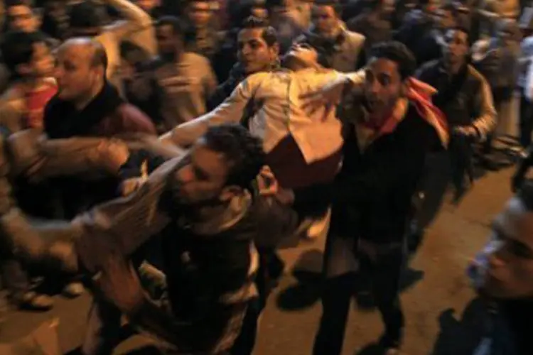 Manifestantes carregam companheiro ferido nos protestos da seamana passada no Cairo, quando 74 foram mortos (Mahmud Hams/AFP)