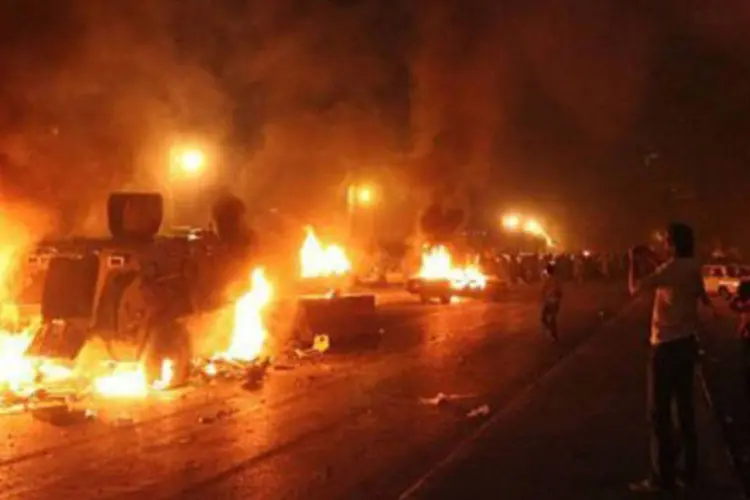 Vários veículos das forças da ordem foram incendiados pelos manifestantes, que estão à espera do funeral dos cristãos mortos no domingo durante choque com militares  (Owaise Mahmoud/AFP)