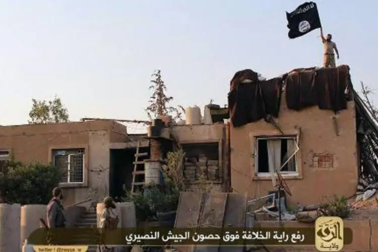 Imagem divulgada pelo EI mostra jihadistas exibindo bandeira em base do exército (AFP)