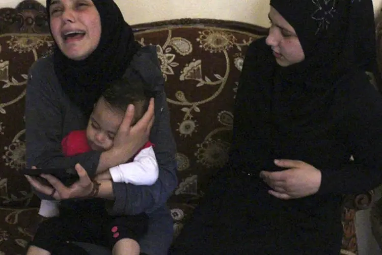 Esposa do soldado libanês decapitado pelo Estado Islâmico (EI) chora com sua filha no colo (Reuters/Stringer)